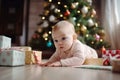 Happy baby child near a Christmas tree decorated with toys with New Year\'s gifts. AI generated Royalty Free Stock Photo