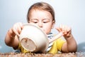 Happy baby child with a spoon. Baby eating. Kid plays in the kitchen with dishes. Happy baby boy spoon eats itself.