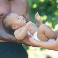 Happy baby. Close up of Biracial baby lying on parents hands. Father and Mother hug Biracial baby child. Multiracial