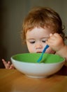 Happy baby eating himself with a spoon. Royalty Free Stock Photo