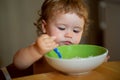 Happy baby eating himself with a spoon. Child nutrition concept. Royalty Free Stock Photo