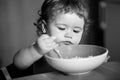 Happy baby eating himself with a spoon. Child nutrition concept. Royalty Free Stock Photo