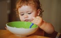 Happy baby eating himself with a spoon. Child nutrition concept. Royalty Free Stock Photo