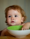 Happy baby eating himself with a spoon. Healthy nutrition for kids. Funny child face closeup. Royalty Free Stock Photo