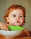 Happy baby eating himself with a spoon. Healthy nutrition for kids. Funny child face closeup. Royalty Free Stock Photo