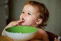 Happy baby eating himself with a spoon. Healthy nutrition for kids. Baby holding a spoon while putting it in his mouth. Royalty Free Stock Photo