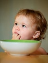 Happy baby eating himself with a spoon. Lick tasty fingers. Royalty Free Stock Photo