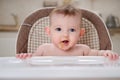 Happy baby with food stained mouth sitting on child chair, home kitchen background Royalty Free Stock Photo