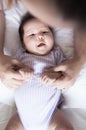 A happy baby gazing up at his or her parent while the parent holds the baby with affection.