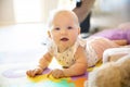 Happy baby girl with blue eyes playing on floor mate Royalty Free Stock Photo