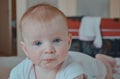 Happy baby girl crawling on the bed. Cute toddler girl lies on the bed smiling. 6 months old baby girl. Portrait of a Royalty Free Stock Photo