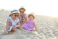 Happy baby girl and her sisters playing in sand on a beautiful beach Royalty Free Stock Photo