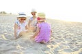 Happy baby girl and her sisters playing in sand on a beautiful beach Royalty Free Stock Photo