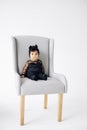 Happy baby girl from interracial marriage sits in armchair on white background