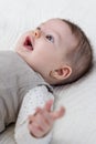 Happy baby girl lying on back over white bedcover Royalty Free Stock Photo