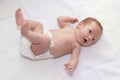 Happy baby girl lying on white sheet wearing a diaper. Cute adorable baby is 1 month old. Royalty Free Stock Photo