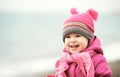 Happy baby girl in pink hat and scarf laughs