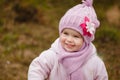 Happy baby girl in a pink hat and scarf laughs in autumn Royalty Free Stock Photo