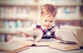 Happy baby girl reading a book in a library Royalty Free Stock Photo