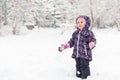 Happy baby girl rejoices in falling snow, Moscow, Russia. Cute little child having fun plays in snowy park