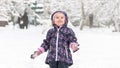 Happy baby girl rejoices in falling snow, Moscow, Russia. Cute little child having fun plays in winter