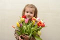 Happy baby girl rejoices and smiles with a bouquet of multi-colored tulips in hands Royalty Free Stock Photo