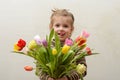 Happy baby girl rejoices and smiles with a bouquet of multi-colored tulips in hands Royalty Free Stock Photo