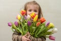 Happy baby girl rejoices and smiles with a bouquet of multi-colored tulips in hands Royalty Free Stock Photo