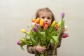 Happy baby girl rejoices and smiles with a bouquet of multi-colored tulips in hands Royalty Free Stock Photo