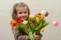 Happy baby girl rejoices and smiles with a bouquet of multi-colored tulips in hands Royalty Free Stock Photo