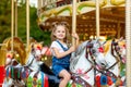 Happy baby girl rides a carousel on a horse in an amusement Park in summer Royalty Free Stock Photo