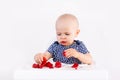 Happy baby girl sitting in high chair eating strawberry in a white kitchen. Healthy nutrition for kids. Bio fruits as first solid Royalty Free Stock Photo