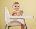 Happy baby girl sitting in highchair