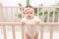 Happy baby girl six months standing in the crib Royalty Free Stock Photo