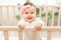 Happy baby girl six months standing in the crib Royalty Free Stock Photo