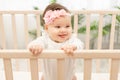Happy baby girl six months standing in the crib Royalty Free Stock Photo