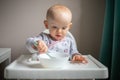 Happy baby girl with spoon sitting in highchair at home Royalty Free Stock Photo