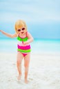 Happy baby girl in sunglasses dancing on beach Royalty Free Stock Photo