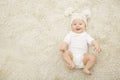 Happy Baby in Hat and Diaper Lying on Carpet Background