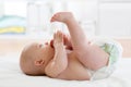 Happy baby infant lying on white sheet and holding her legs Royalty Free Stock Photo
