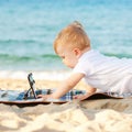 Happy baby kid with technology on beach Royalty Free Stock Photo