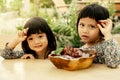 Happy baby and kid wearing twin clothes sitting on the table with a plate of grapes freeze in ice, eat healthy fruit childhood Royalty Free Stock Photo