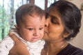 Happy Baby Loves mom Kisses. Loving Mother kissing cute little adorable kid on her lap. Close-up portrait. Indian ethnicity. Front