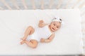 Happy baby is lying in a crib in the children`s room on a white bed Royalty Free Stock Photo