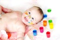 Happy baby lying among finger-type paints