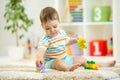 Happy baby playing with colorful plastic bricks on the floor. Toddler having fun and building a train out of constructor