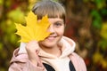 Happy baby resting in the autumn nature. A child enjoys the autumn weather in the forest. A girl holds a maple leaf in an autumn Royalty Free Stock Photo