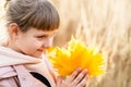 Happy baby resting in the autumn nature. A child enjoys the autumn weather in the forest. A girl holds a maple leaf in an autumn Royalty Free Stock Photo