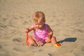 Happy baby in sand plays. Cheerful little kid playing on beach on sunny day. Royalty Free Stock Photo