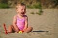 Happy baby in sand plays. Cheerful little kid playing on beach on sunny day. Royalty Free Stock Photo